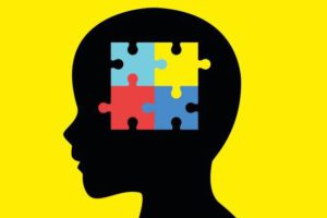 Children head silhouette with colorful jigsaw puzzle symbolizing autism